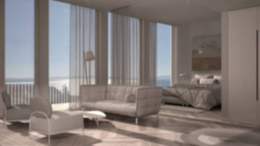 模糊背景室内设计一居室公寓，拼花地板，开放空间客厅有沙发，扶手椅，卧室有床和毯子。带窗帘的全景窗