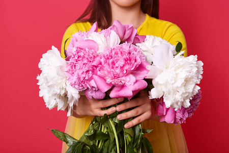 连衣裙的陌生女性双手捧着一束白色和粉色的牡丹花,照片中间是鲜花