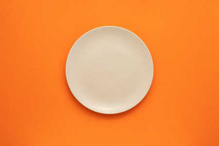 Top view empty white ceramic dish on the middle of orange 