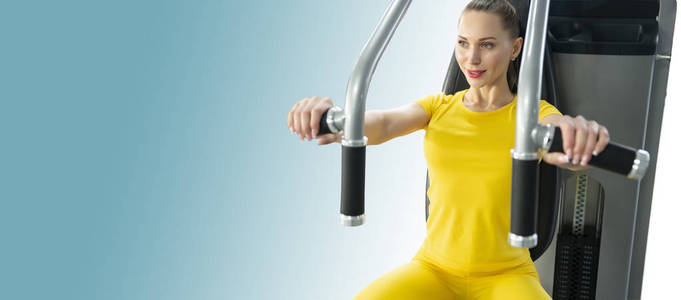蓝色背景下，一位快乐的年轻白人妇女在健身机上锻炼