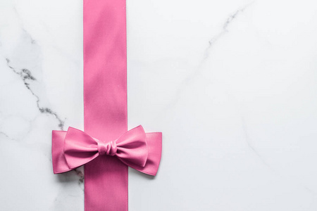 Pink silk ribbon and bow on marble background, girl baby shower 