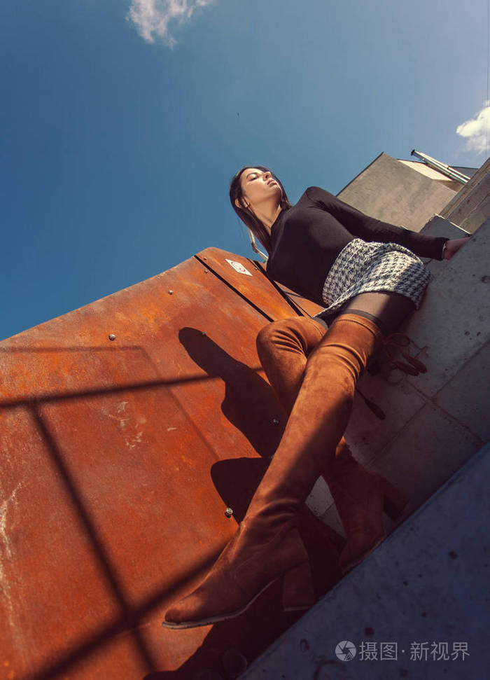 时髦的女模特坐在大楼的台阶上摆姿势