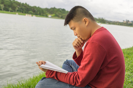 亚洲男人坐在草地上看书图片