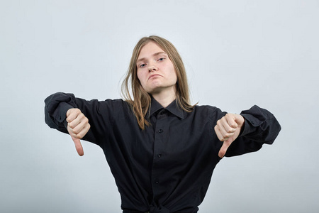 一个失望的白人金发女人把大拇指朝下，看起来很不高兴。