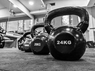 各种颜色和尺寸的圆形壶铃球哑铃排列在健身房的地板上，可用于减肥和健身