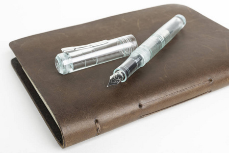 棕色皮革日记本和绿色玻璃钢笔图片