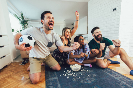 Group of cheerful friends watching soccer match and celebrating 