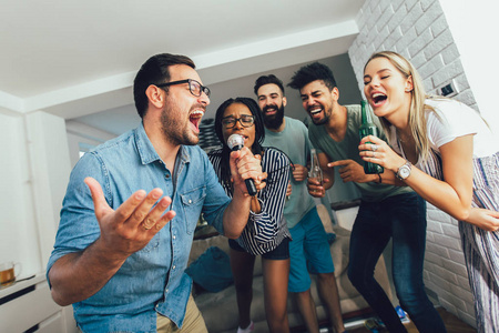快乐的朋友在家里一起唱歌。卡拉OK派对概念