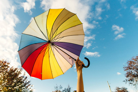  young woman standing with a multicolored umbrella and rotates 