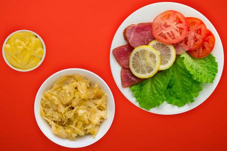  ham with lettuce, tomatoes and lemon on a white plate. ham on a