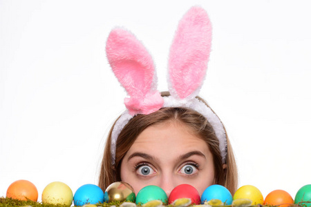 春天，青草上画着彩蛋的年轻女子。复活节快乐概念。可爱的女孩与装饰复活节彩蛋孤立在白色背景。复活节那天，一个惊喜的女孩戴着兔子耳朵
