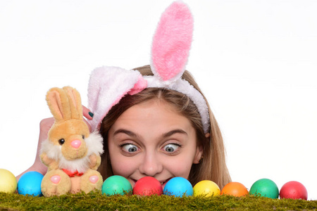 疯狂的小女孩戴着兔子耳朵，看着五颜六色的彩蛋。传统的复活节装饰品。复活节假期快乐概念。