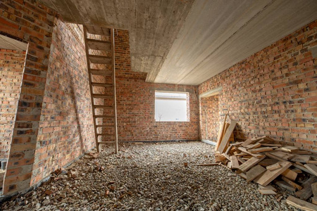 Interior of unfinished brick house with concrete floor and bare 