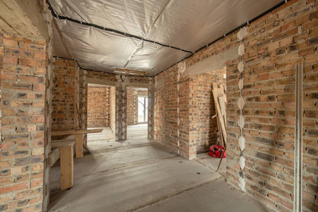 Interior of unfinished brick house with concrete floor and bare 