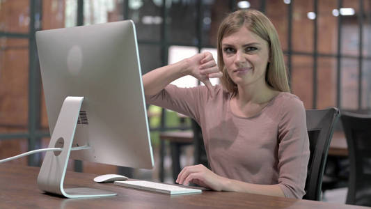 一位年轻女子在电脑工作时竖起大拇指