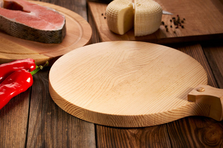 Empty serving board is on a wooden table with ingredients around