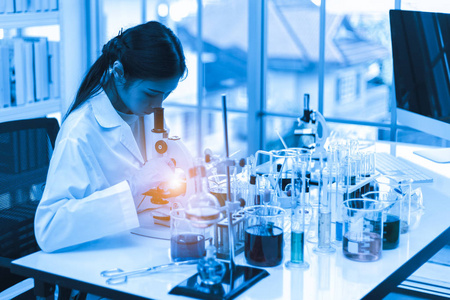亚洲女科学家用显微镜和科学实验设备在实验室进行科学研究照片