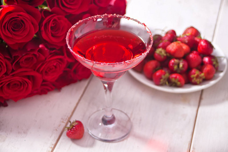 红色异域酒精鸡尾酒在透明玻璃和红色玫瑰花瓣混凝土上浪漫晚餐.