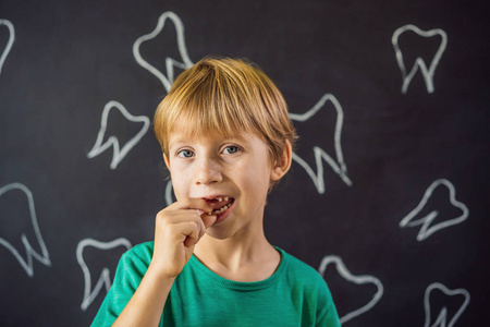 瘦小的白人男孩用手指夹着掉下来的乳牙,笑着看着镜头照片