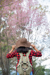 Asian girl traveler with backpack holding hat and looking at Sak