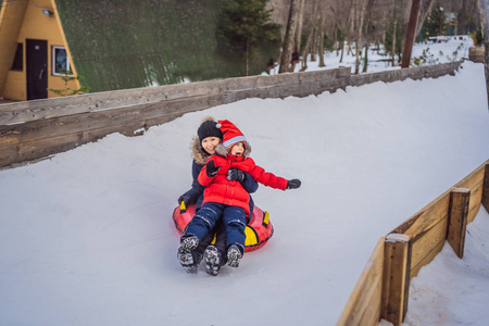 妈妈和儿子坐在充气的冬季雪橇管上。全家过冬的乐趣