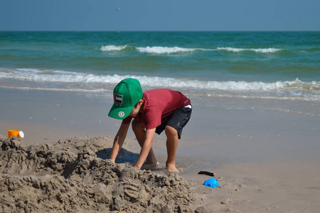 沙雕城堡一个男孩在沙滩上玩.这孩子造沙雕.海滩上的玩具.