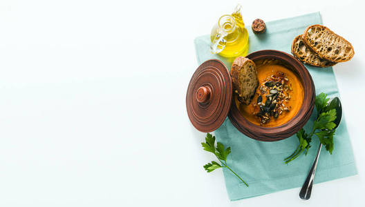 banner of pumpkin soup with seeds and fresh rye bread in a clay 