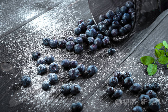 黑色木质背景玻璃杯中的有机新鲜蓝莓