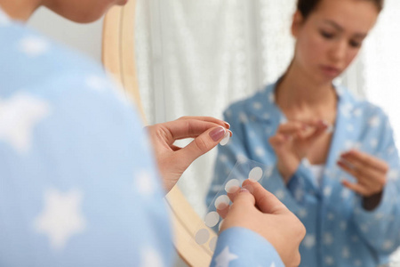 十几岁的女孩在浴室镜子附近敷痤疮愈合贴片