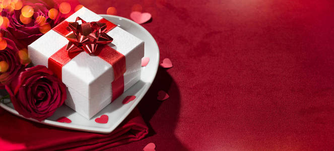 心形盘子上的礼品盒和红色封面上的玫瑰