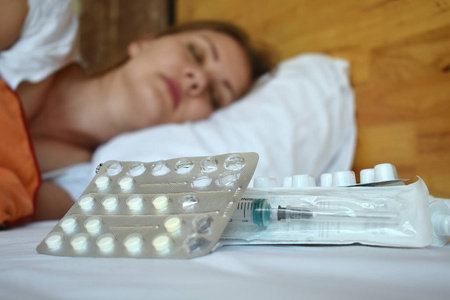 Young woman with pills in bed. Headache the girl. A tired woman 