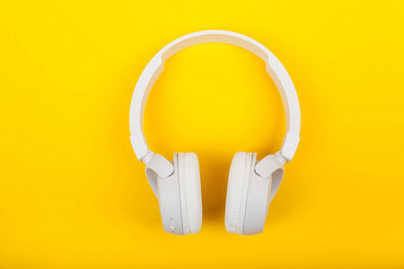 Wireless white headphones on yellow background. Music concept. E