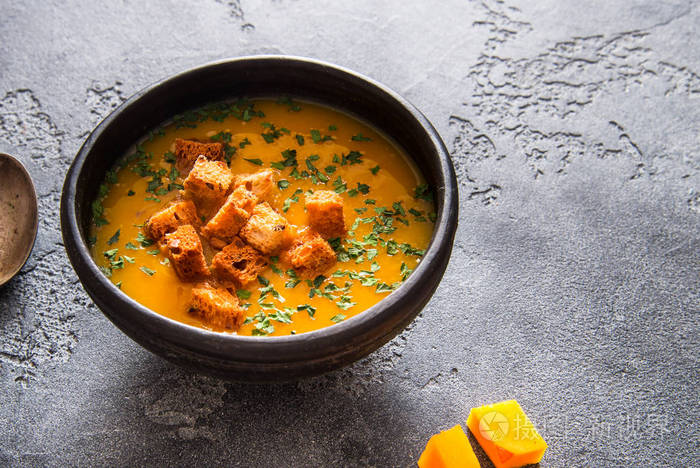 黑色陶瓷碗中的纯素南瓜汤背景为深色俯视图