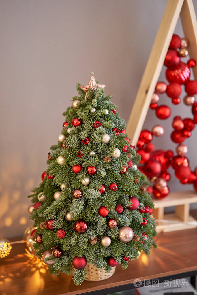 木制桌子上漂亮的小圣诞树。心情愉快。背景上有花环灯。墙纸。丹麦松树和冷杉