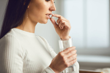 药片在房间里的女孩手里。概念病毒感冒丸病流感病头痛流感病