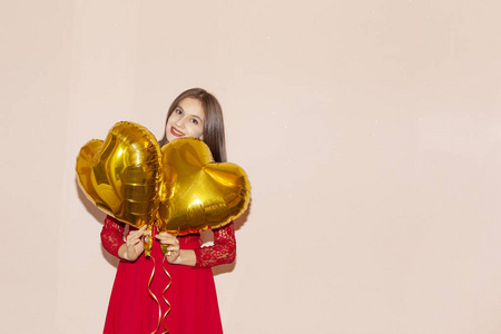 女人拿着心形的金色气球。情人节，生日，妇女节，周年纪念，节日庆祝概念