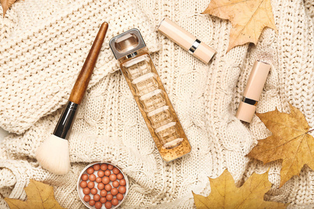 针织毛衣上的一瓶香水和化妆品的秋季构图