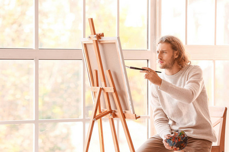 年轻男画家在画室作画照片
