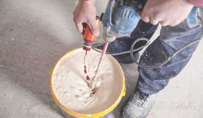 拿着钻头搅拌油漆的人翻新