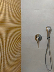 浴室内配有淋浴头的现代淋浴间，室内设计清凉，采用浅木色风格