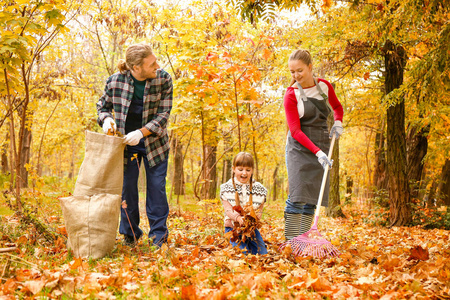 一家人在户外清理秋叶图片
