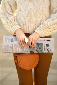 时尚的年轻女人在户外拿着报纸，特写
