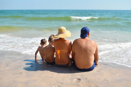 Family sitting on the sand on the beach. Family holidays by the 