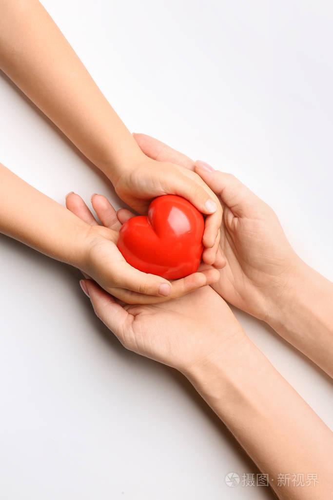 白底红心儿童和成人的手.心脏病学概念