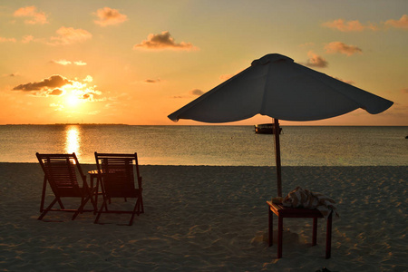 雨伞和日光浴床面向印度洋和美丽的日落。