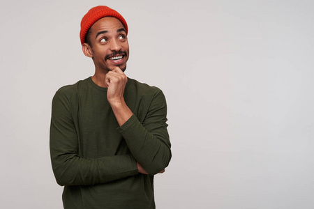 年轻活泼可爱的黑胡子男性,深色皮肤,手放在下巴上,微笑愉快,穿着红