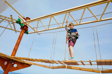 勇敢的孩子快乐的小男孩在高绳道上攀爬.