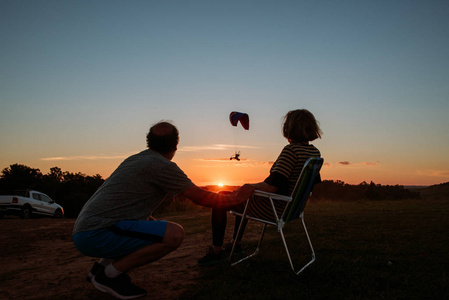 人们在日落时观看滑翔伞