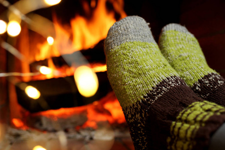 袜子细节冬天的傍晚,一个女人穿着针织袜子在壁炉旁取暖照片