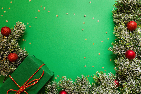圣诞包装的礼品盒和树枝在绿色的背景和五彩纸屑。新年概念。贺卡，圣诞庆祝2020。平面布置模板俯视图复印空间
